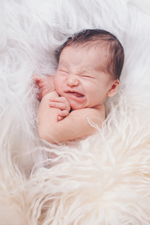 Portrait of newborn baby on a white background. the child makes a faceの写真素材