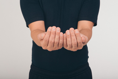 A man in a black t-shirt holds his hands in front of him palms upの写真素材