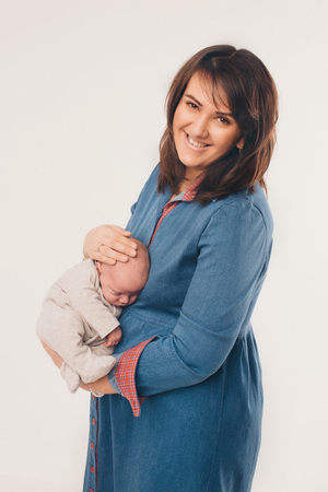 a newborn baby sleeps in the arms of his mother in a blue dress. Isolated family photoの写真素材