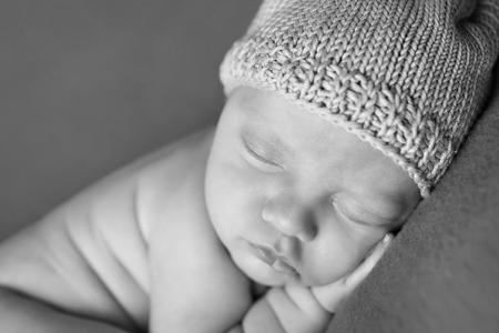 newborn baby lying on a white and black background. Imitation of a baby in the womb. beautiful little child sleeping lying on her tummy. Portrait of newbornの写真素材