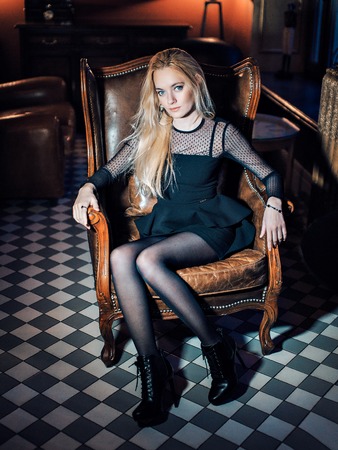 Portrait of a blue-eyed blonde in black clothes. Beautiful girl looking at the camera. Woman with loose hairの写真素材
