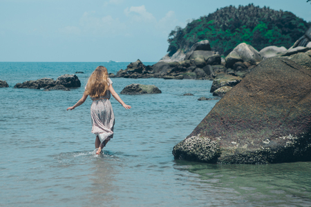 handsome girl on the beach background. Portrait of a woman in white clothes on the seaの写真素材