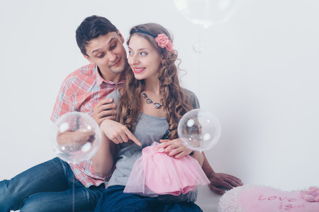 pregnant woman and ,man playing with rattle on floor on white backgroundの写真素材