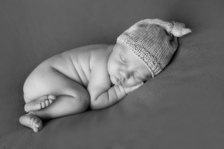 newborn baby lying on a white and black background. Imitation of a baby in the womb. beautiful little child sleeping lying on her tummy. Portrait of newbornの写真素材