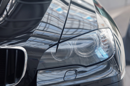 Cropped photo: a black car front light close-up. business class carの写真素材