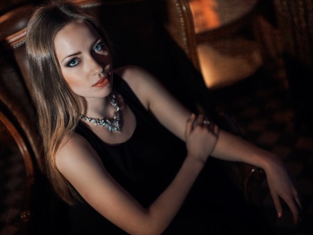 beautiful girl in a long black dress sitting in a chairの写真素材