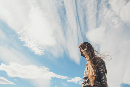 silhouette of a girl with long-hair against the clouds. portrait of woman: posing on a sky background.の写真素材