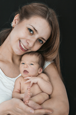 newborn baby lying on the hands of parents on a black background. Mother and daugheter. manifestation of love of a woman to a childの写真素材