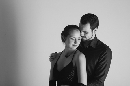 portrait: man in suit and woman in dress on white background. pair in an isolated photo. Husband hugs wifeの写真素材