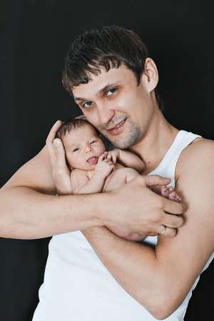 newborn baby lying on the hands of parents on a black background. Father and daugheter. manifestation of love of a man to a childの写真素材