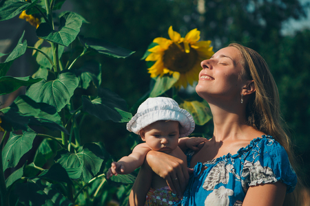 Portrait of a girl and baby with flower on a background of green foliageの写真素材