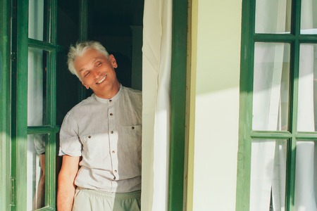 a gray-haired man in bright clothes standing in the doorwayの写真素材