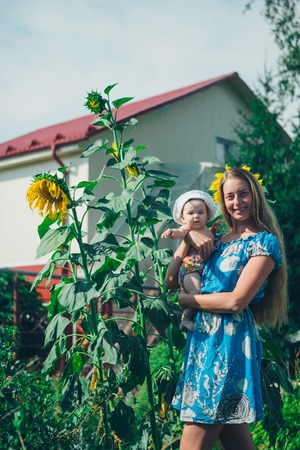 Portrait of a girl and baby with flower on a background of green foliageの写真素材