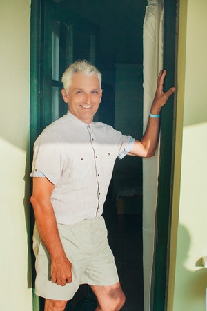 A gray-haired man in bright clothes standing in the doorwayの写真素材