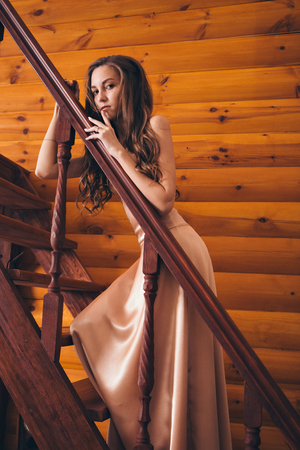 beautiful girl posing on the stairs in a pink long dress. Model in evening dress for promの写真素材