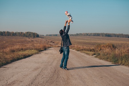 A man with a child in his arms on the road in the middle of a wastelandの写真素材