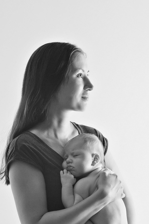 mother holds on the hands of his bare newborn baby. Woman with a baby in her arms on a white and black backgroundの写真素材