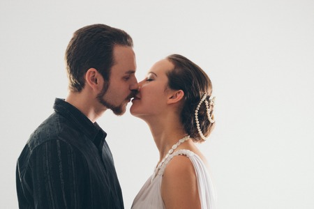 portrait: man and woman kissing on white background. The bride and groom in an isolated photo. Husband and wife face to faceの写真素材