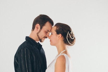 portrait: man and woman kissing on white background. The bride and groom in an isolated photo. Husband and wife face to faceの写真素材