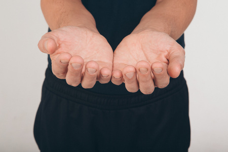 A man in a black t-shirt holds his hands in front of him palms upの写真素材