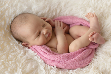A little child in a pink diaper lies on a beige backgroundの写真素材