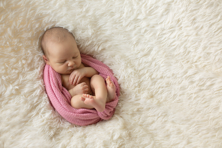 A little child in a pink diaper lies on a beige backgroundの写真素材