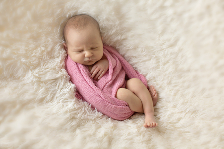 A little child in a pink diaper lies on a beige backgroundの写真素材