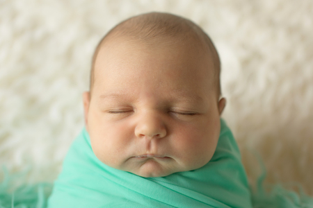 A little child in a greeen diaper lies on a beige backgroundの写真素材