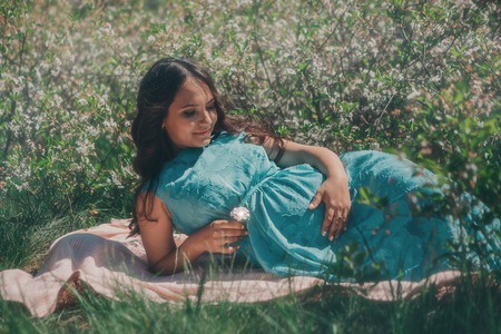 portrait of a young girl: a pregnant woman lying on the ground on a grass backgroundの写真素材