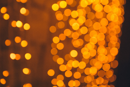 Many blurred small electric bulbs on a wall. Yellow blurred lights. Wall of Christmas lightsの写真素材