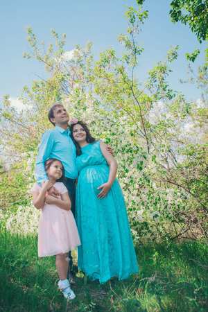 man, pregnant woman and little girl: family photo outdoors. fashion for the whole familyの写真素材