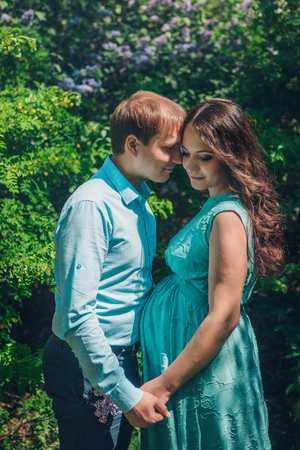Man hugs his pregnant woman from behind standing in the forestの写真素材