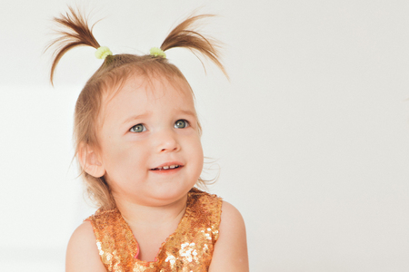 portrait of a little girl with tails on white background. Baby plays with toysの写真素材