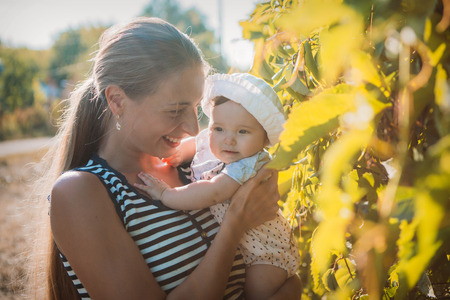 Portrait of a girl with baby on a background of green foliageの写真素材