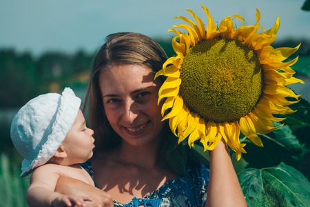 Portrait of a girl with baby and flower on a background of green foliageの写真素材