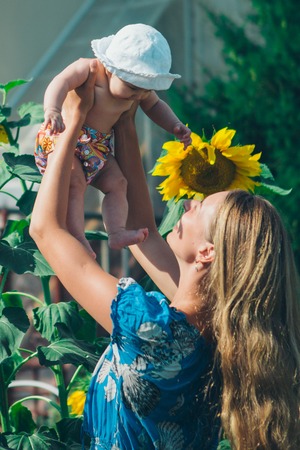 Portrait of a girl with baby and flower on a background of green foliageの写真素材