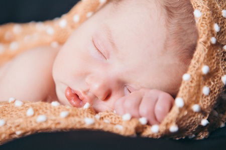 A little child in a beige diaper lies on a black backgroundの写真素材