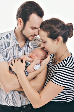 newborn baby lying on the hands of parents on a white background.の写真素材
