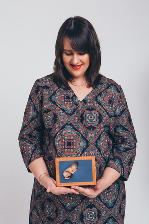 a pregnant woman holding a photo of her unborn child. Isolated photo on white backgroundの写真素材