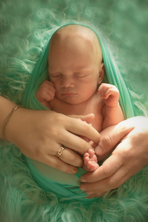 A little child in a green diaper lies on a green backgroundの写真素材