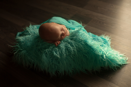 A little child in a green diaper lies on a black backgroundの写真素材