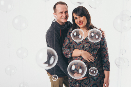 Family portrait: the husband embraces the pregnant wife on a white background. pregnant couple in loveの写真素材