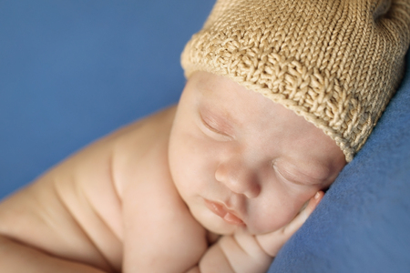 newborn baby lying on a blue background. Imitation of a baby in the womb. beautiful little child sleeping lying on her tummy. Portrait of newbornの写真素材