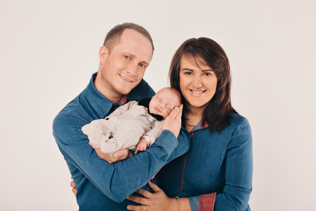 newborn baby lying on the hands of parents on a white background.の写真素材