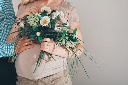 Pregnant woman in long dress with flowers on white backgroundの写真素材