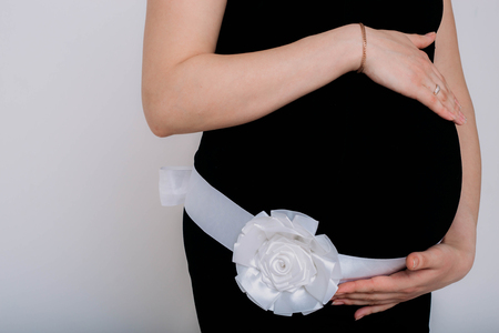 Pregnant woman in balck dress with flower on white backgroundの写真素材