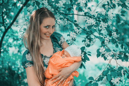 Portrait of a girl with baby on a background of green foliageの写真素材