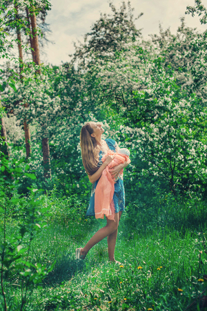 Portrait of a girl with baby on a background of green foliageの写真素材