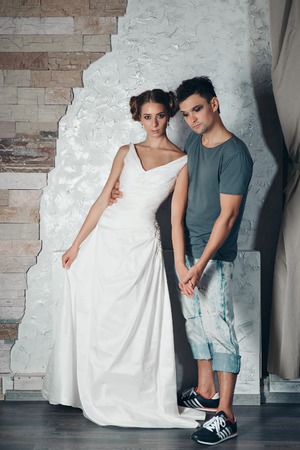 guy with makeup hugs a girl in a white dress with a crown. Beauty and the beast these days. Portrait of man and womanの写真素材