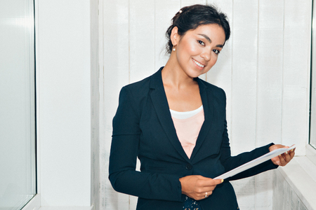 girl in a business suit Asian appearance on a white background in the office working with documentsの写真素材